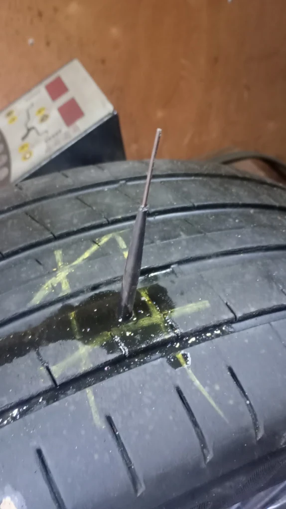 Close-up of a nail puncture through a tyre tread